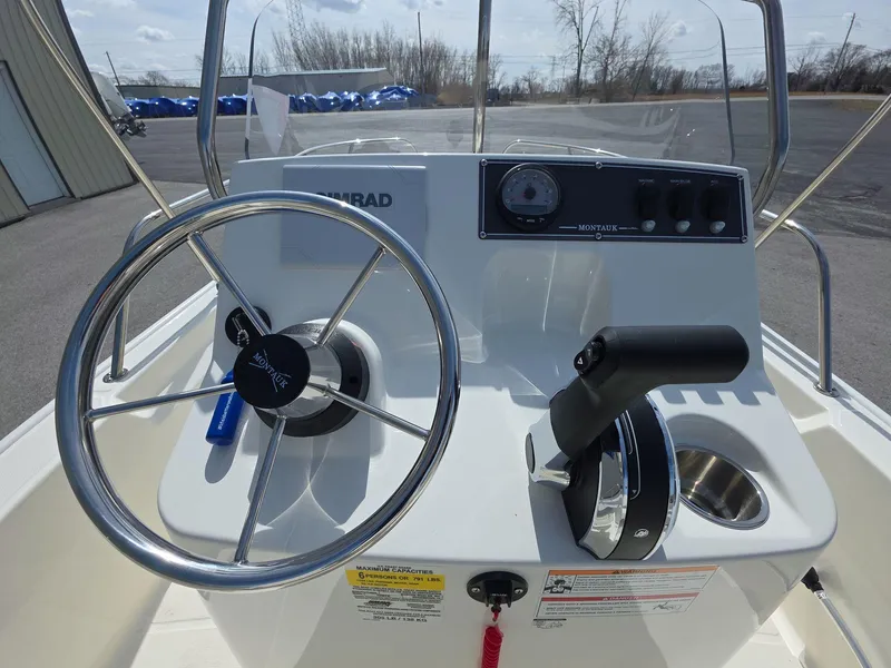 Slide: The Image of 2024 Boston Whaler 150 Montauk boat console with steering wheel and controls. - 7