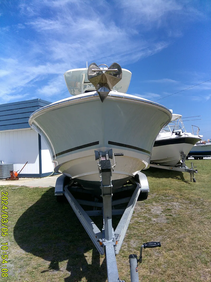 Slide: The Image of 2021 Boston Whaler Outrage 230 boat on trailer, parked outdoors under a clear blue sky. - 3