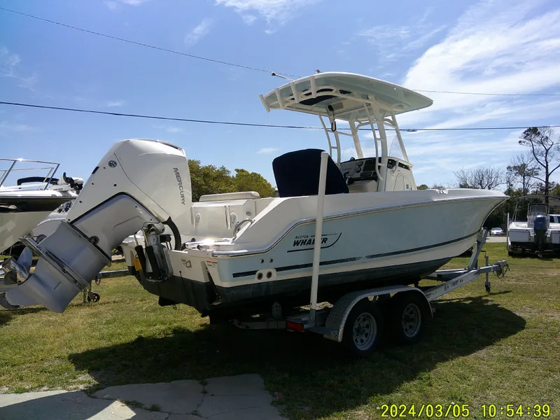 Slide: The Image of 2021 Boston Whaler Outrage 230 boat on trailer, parked on grass under clear sky. - 7