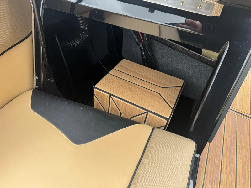 Slide: The Image of 2022 Moomba Makai interior detail with tan and black seating and storage compartment. - 15