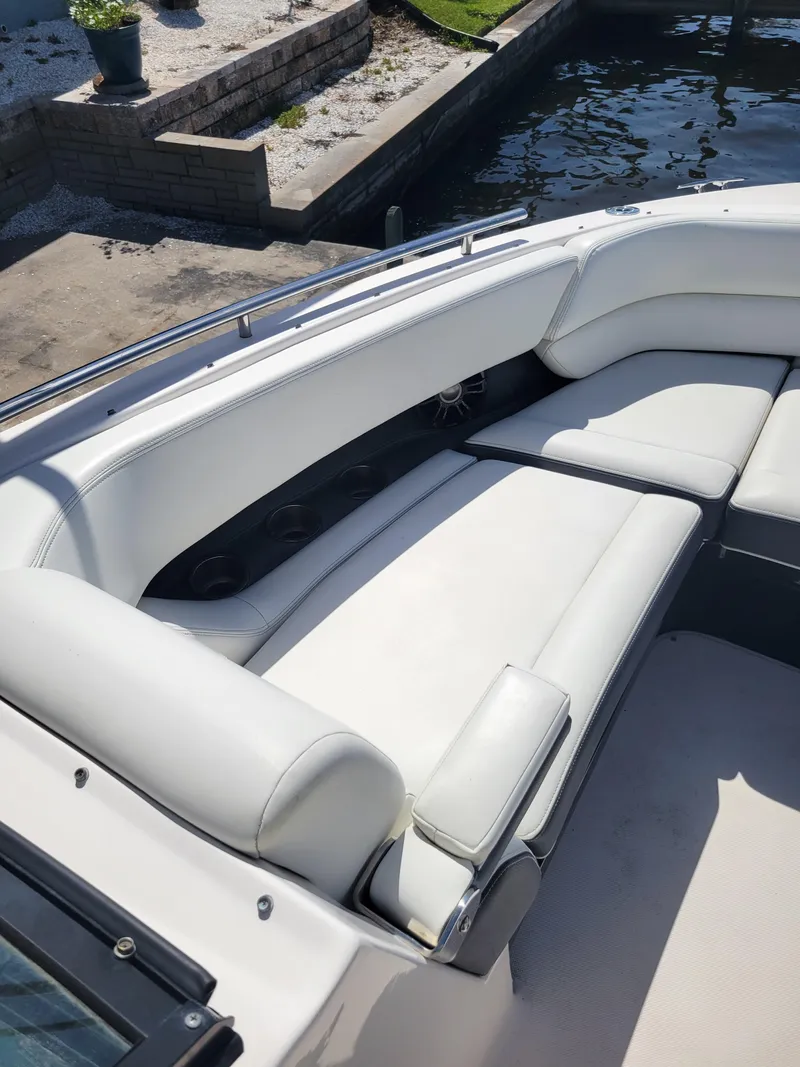 Slide: The Image of 2020 Regal 29 OBX boat with white leather seating, docked by a stone wall. - 11