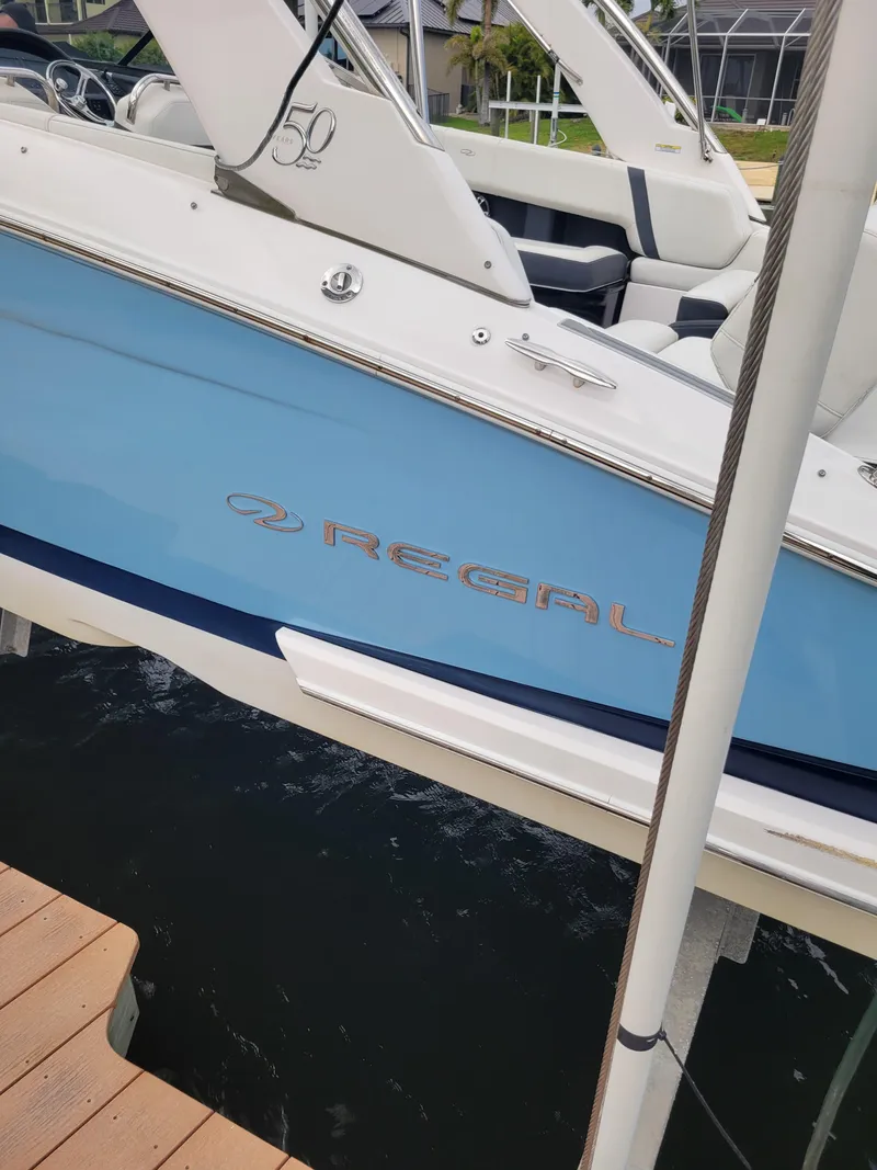 Slide: The Image of 2020 Regal 29 OBX boat with blue hull docked at marina. - 2