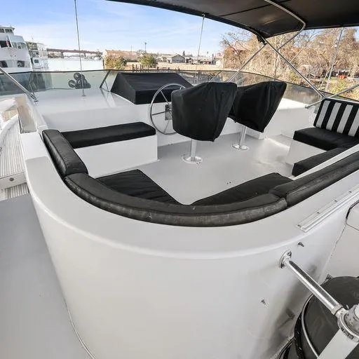 Slide: The Image of 1991 Vic Franck 65 Motor Yacht flybridge with seating and steering wheel, docked by the water. - 19
