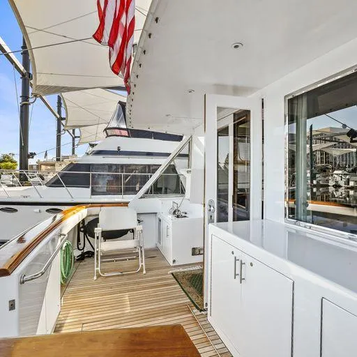 Slide: The Image of 1991 Vic Franck 65 Motor Yacht deck with seating, American flag, and marina view. - 25