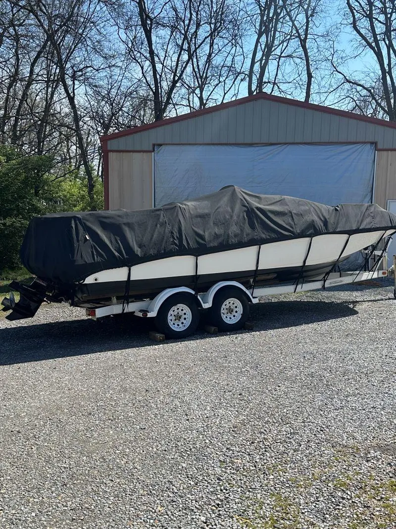 Slide: The Image of 1998 Sea Ray 240 Sundeck boat covered on trailer, parked outside a garage. - 17