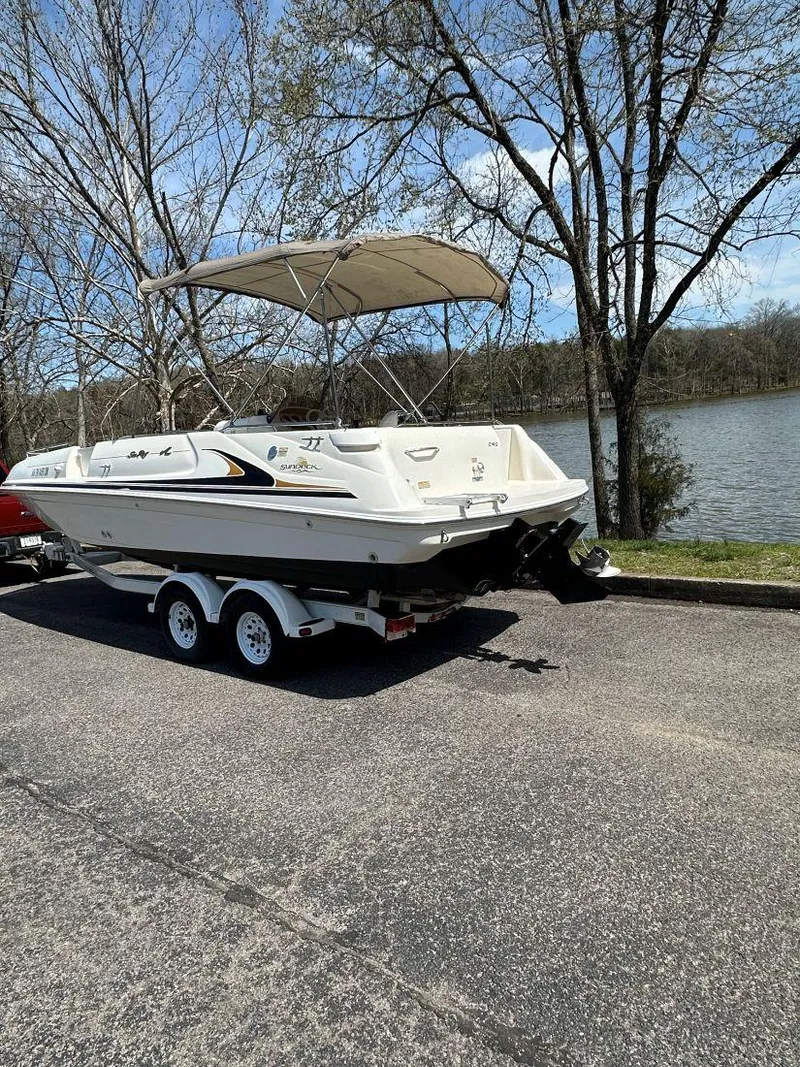 Slide: The Image of 1998 Sea Ray 240 Sundeck boat on trailer by a lake, under clear sky. - 3