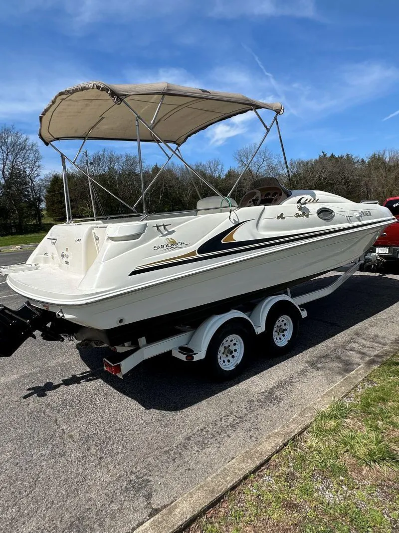 Slide: The Image of 1998 Sea Ray 240 Sundeck boat on trailer, parked outdoors under blue sky. - 4