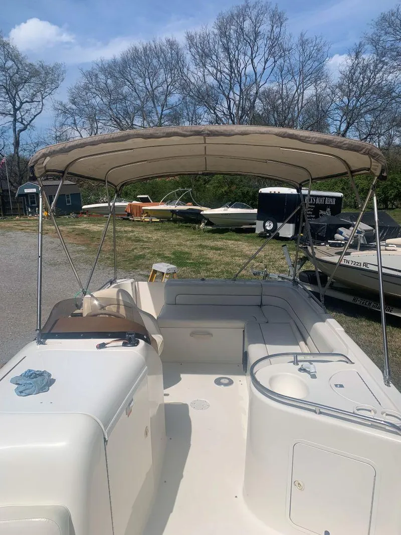Slide: The Image of 1998 Sea Ray 240 Sundeck boat with canopy, parked outdoors under a clear sky. - 7