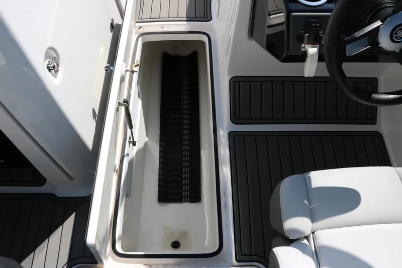 Slide: The Image of 2018 Yamaha Boats AR240 HO interior storage compartment with seating and steering wheel. - 34