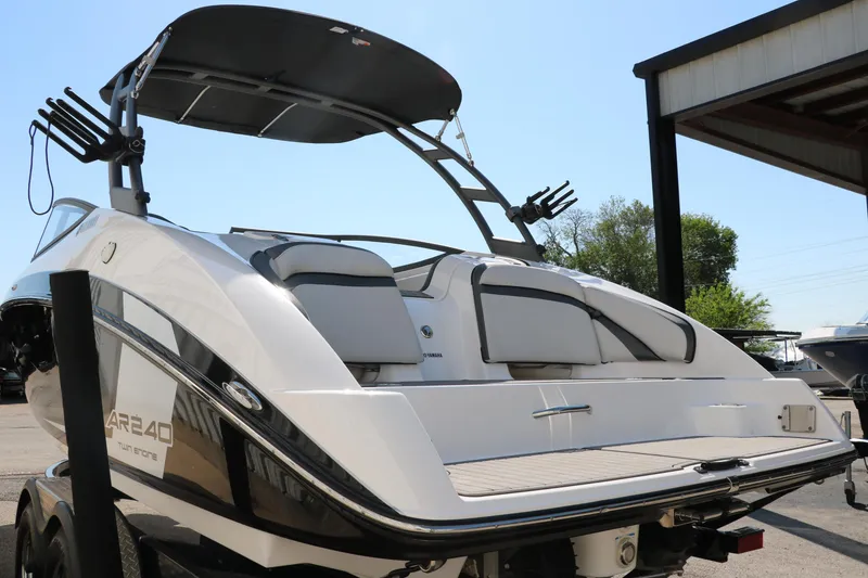 Slide: The Image of 2018 Yamaha Boats AR240 HO, sleek design, rear view, docked under sunny sky. - 6