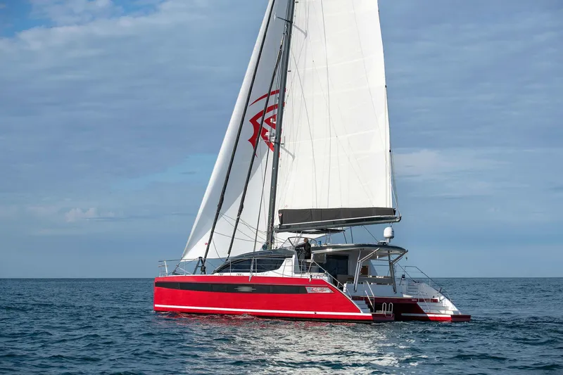 Slide: The Image of 2025 Privilege Signature 510 catamaran sailing on open sea with red and white design. - 13