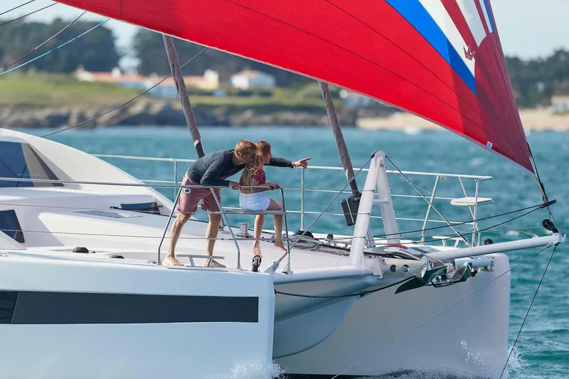 Slide: The Image of Couple enjoying sailing on 2025 Privilege Signature 510 catamaran with vibrant red sail. - 22