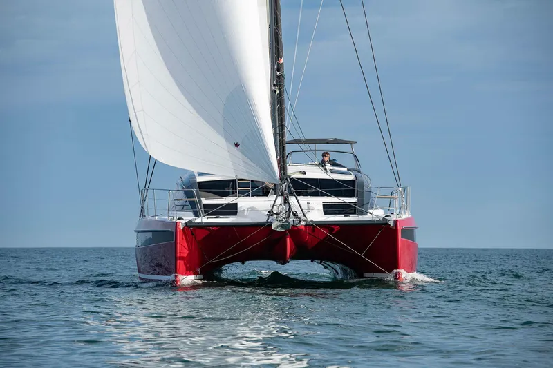 Slide: The Image of 2025 Privilege Signature 510 catamaran sailing on open water, featuring a striking red hull. - 28