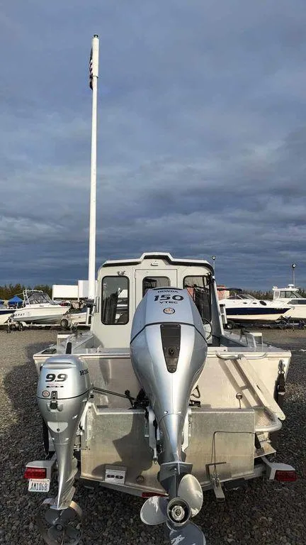 Slide: The Image of 2018 Hewescraft 210 Sea Runner boat with dual outboard motors, parked on gravel. - 4