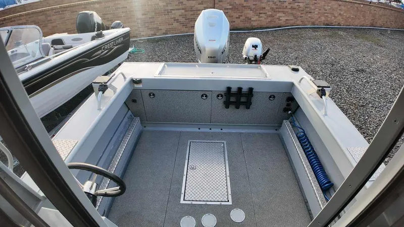 Slide: The Image of 2018 Hewescraft 210 Sea Runner boat interior with motor, docked on gravel. - 5