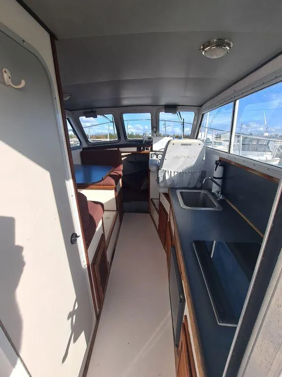 Slide: The Image of Interior of a 2000 Osprey 26 Fisherman boat, featuring a compact kitchen and seating area. - 11