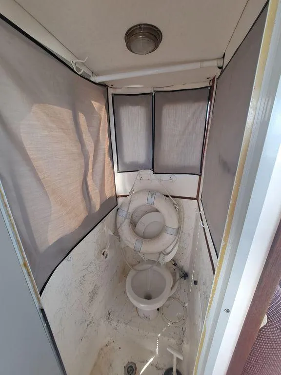 Slide: The Image of Boat bathroom interior on a 2000 Osprey 26 Fisherman, featuring a compact toilet and life preserver. - 12