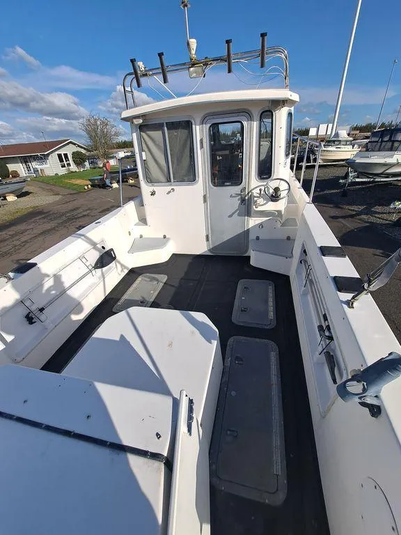 Slide: The Image of 2000 Osprey 26 Fisherman boat with spacious deck and cabin, docked under clear skies. - 16