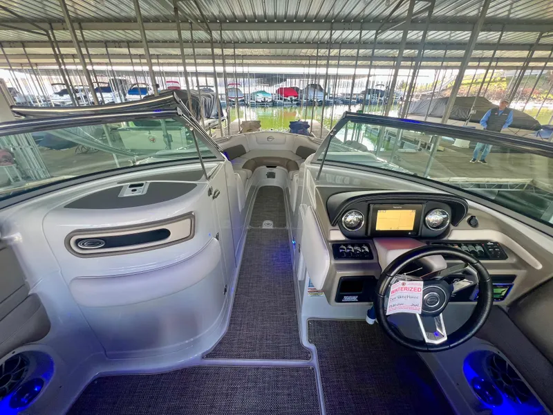 Slide: The Image of 2018 Crownline 285 SS boat interior with modern dashboard and seating under covered dock. - 13