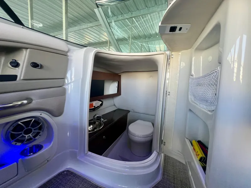 Slide: The Image of Interior of 2018 Crownline 285 SS boat featuring a compact bathroom with sink and toilet. - 25