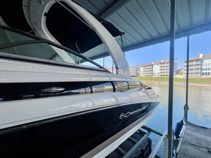 Slide: The Image of 2018 Crownline 285 SS boat docked under a covered marina with waterfront view. - 3
