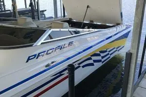 Slide: The Image of 2002 Profile 33 V speedboat with vibrant racing stripes docked on water. - 3