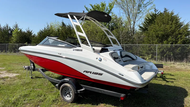 Slide: The Image of 2024 Yamaha Boats AR195 on trailer, red and white, parked on grass. - 10