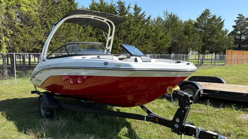 Slide: The Image of 2024 Yamaha AR195 boat with red hull on a trailer, parked outdoors. - 11