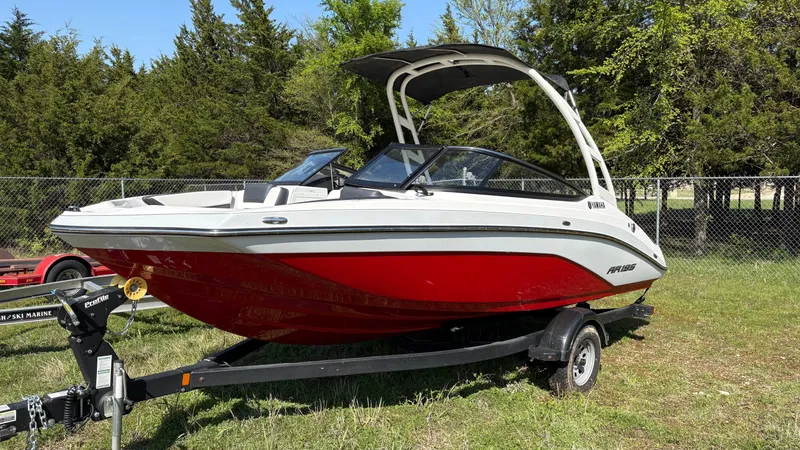 Slide: The Image of 2024 Yamaha AR195 boat with red and white design on a trailer, parked on grass. - 9