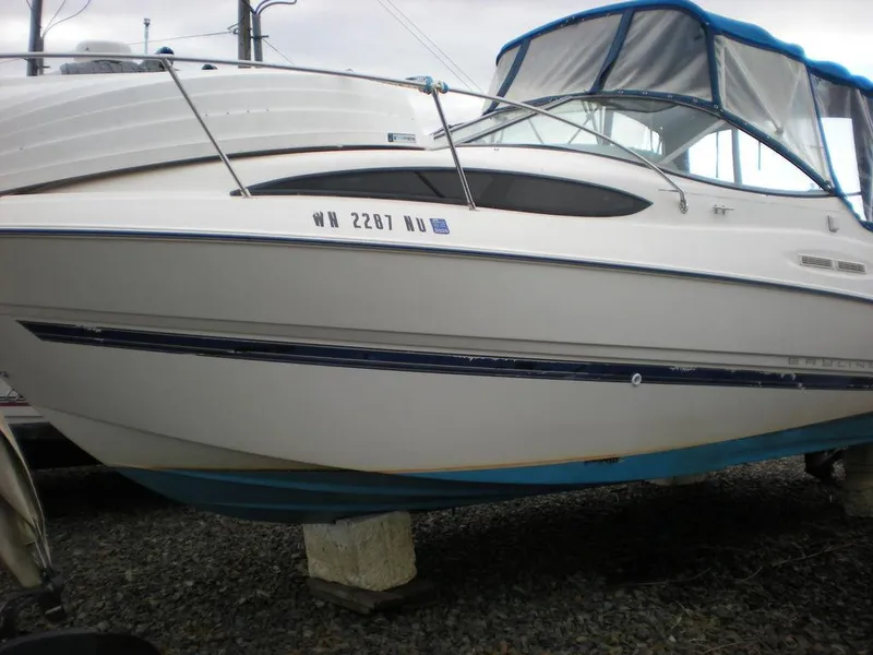 Slide: The Image of 2006 Bayliner 245 SB boat with blue canopy, displayed on a gravel surface. - 1