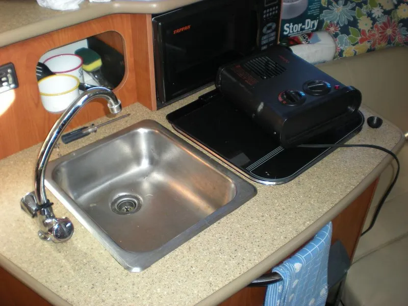 Slide: The Image of 2006 Bayliner 245 SB galley with sink, microwave, and portable stove. - 10