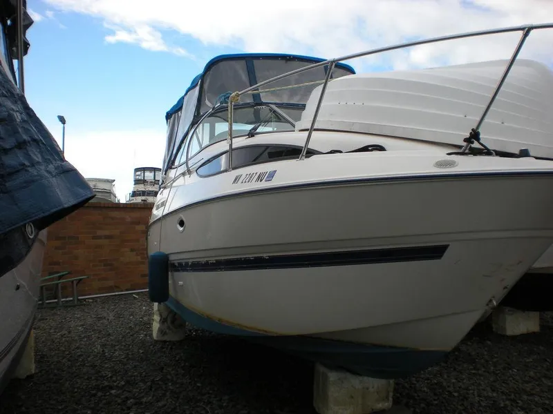 Slide: The Image of 2006 Bayliner 245 SB boat on dry dock, partially covered, with clear sky background. - 3