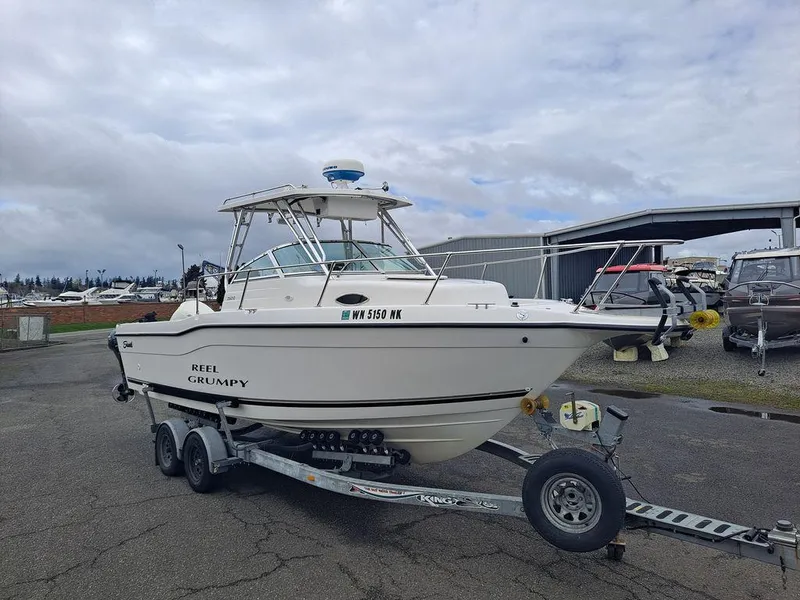 Slide: The Image of 2000 Seaswirl 2501 boat on trailer, parked outdoors under cloudy sky. - 1