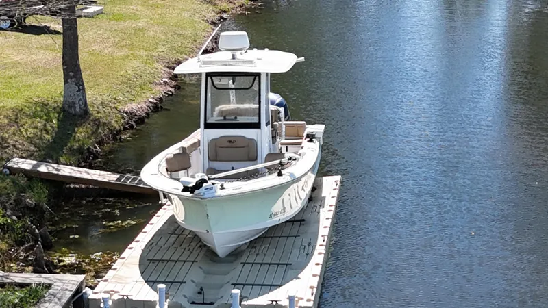Slide: The Image of 2018 Sea Hunt Ultra 235 SE boat docked on a calm river. - 2
