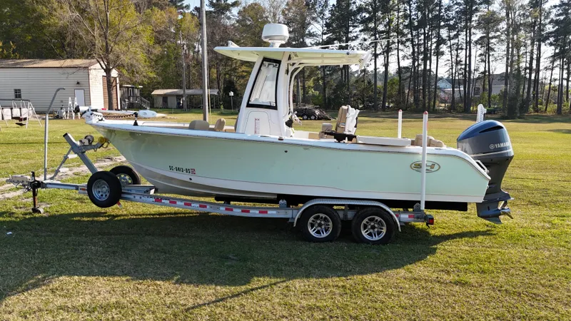 Slide: The Image of 2018 Sea Hunt Ultra 235 SE boat on trailer, parked on grass with trees in background. - 4