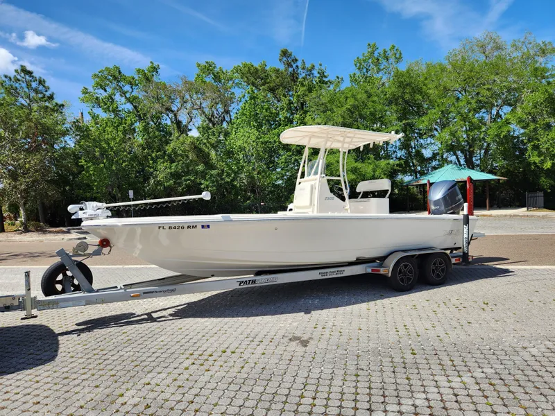 Slide: The Image of 2018 Pathfinder 2500 Hybrid boat on trailer, parked outdoors with trees in background. - 2