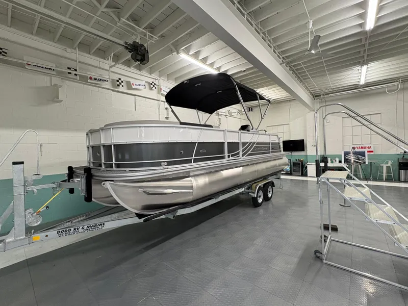 Slide: The Image of 2025 South Bay 224UL pontoon boat on trailer in indoor showroom. - 0