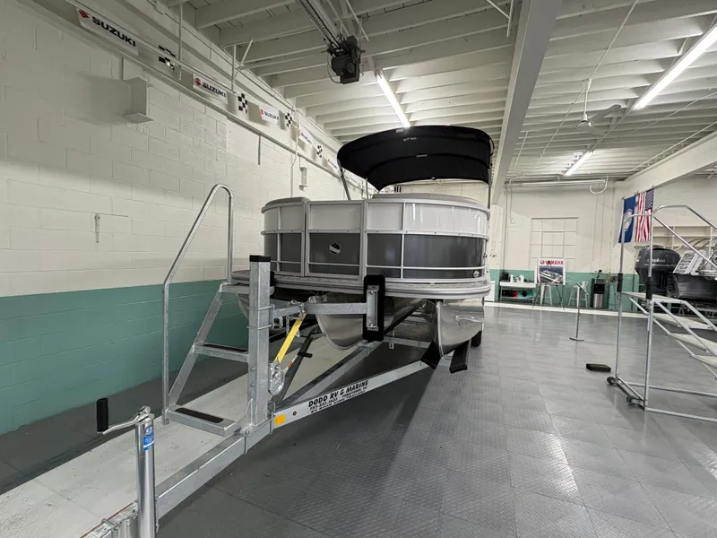Slide: The Image of 2025 South Bay 224UL pontoon boat displayed indoors on a trailer. - 1