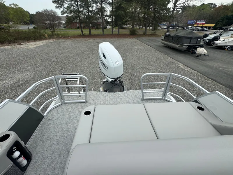 Slide: The Image of 2025 South Bay 224UL pontoon boat with outboard motor, parked on gravel lot. - 10