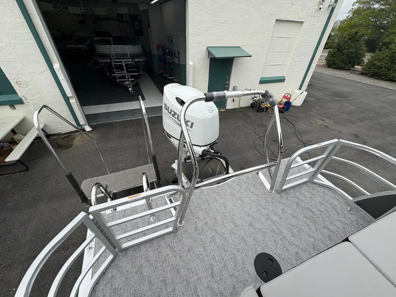 Slide: The Image of 2025 South Bay 224UL pontoon boat with Suzuki outboard motor in a driveway. - 16