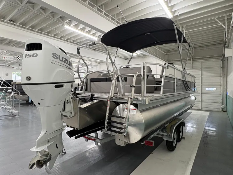 Slide: The Image of 2025 South Bay 224UL pontoon boat with Suzuki 150 outboard motor in showroom. - 2