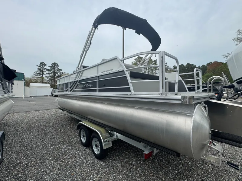 Slide: The Image of 2025 South Bay 224UL pontoon boat on a trailer, parked outdoors. - 8