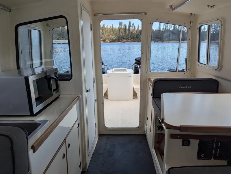 Slide: The Image of Interior of 2008 C-Dory 255 TOMCAT boat with kitchenette and seating, overlooking water. - 20