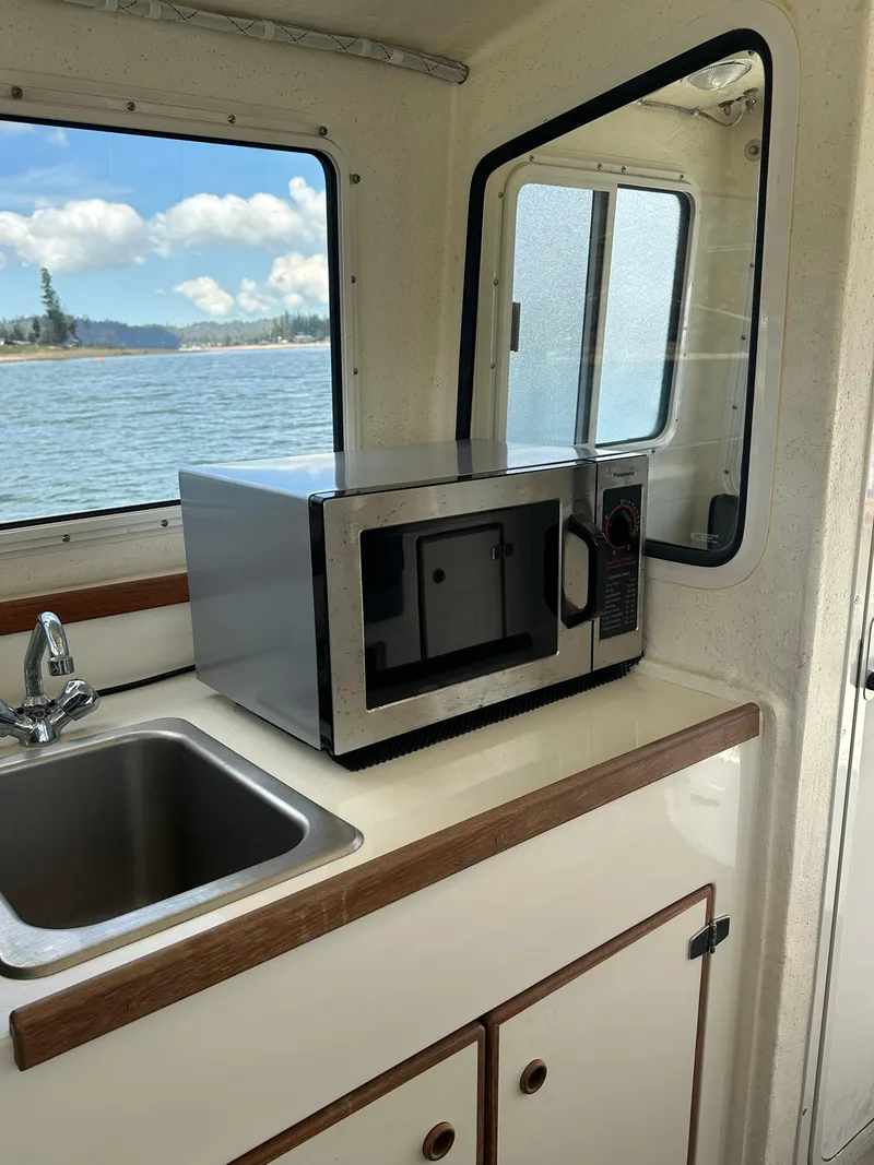 Slide: The Image of 2008 C-Dory 255 TOMCAT interior with microwave and sink, overlooking scenic water view. - 23