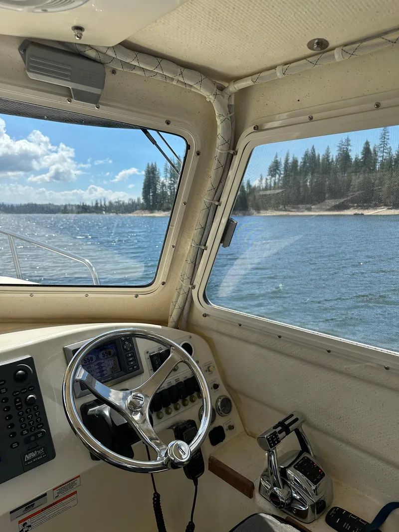 Slide: The Image of Interior view of 2008 C-Dory 255 TOMCAT boat with steering wheel and scenic waterway. - 26