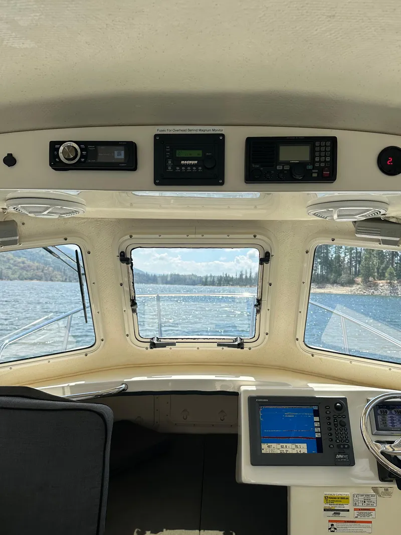 Slide: The Image of Interior view of 2008 C-Dory 255 TOMCAT boat cockpit with navigation equipment and scenic water view. - 28