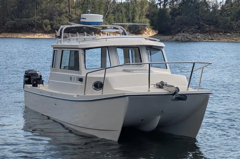 Slide: The Image of 2008 C-Dory 255 TOMCAT boat on a serene lake with forested shoreline. - 3