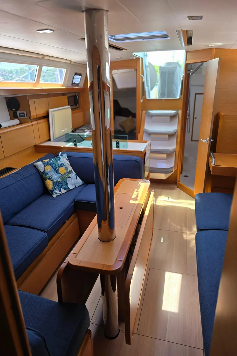 Slide: The Image of Interior of 2017 Jeanneau Sun Odyssey 389 sailboat with blue seating and wooden finishes. - 11