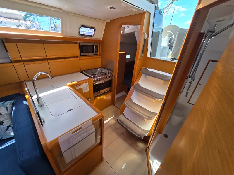 Slide: The Image of Interior of 2017 Jeanneau Sun Odyssey 389 sailboat, featuring modern kitchen and wooden cabinetry. - 44