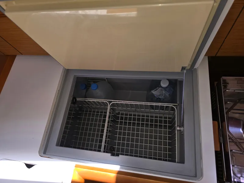 Slide: The Image of Open fridge compartment on 2017 Jeanneau Sun Odyssey 389 yacht, showing interior storage space. - 46
